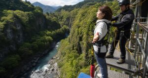 洋服姿の女性が山の渓谷にあるバンジー台で安全確認を受ける利用イメージ