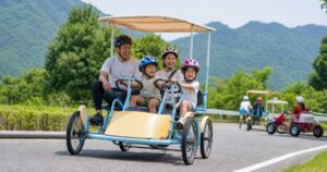 洋服姿の家族が山あいのコースで四人乗り自転車を楽しむ利用イメージ