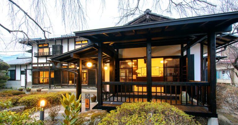 山を望む旅籠屋丸一の建物と到着客を迎える玄関の灯り