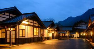 夕暮れの山並みと灯りがともる猿ヶ京温泉の旅籠屋丸一