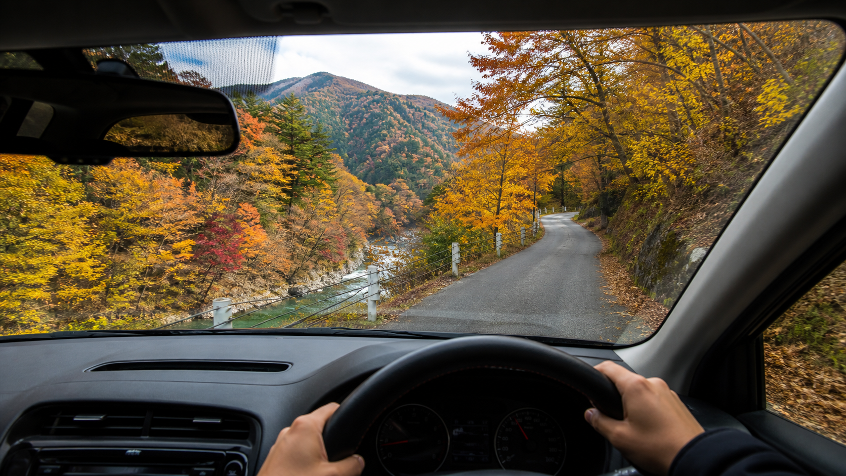 紅葉の狭い山道を両手で運転する照葉峡ドライブの利用イメージ