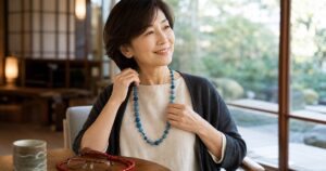 旅籠屋のラウンジで青い糸玉ネックレスを洋服に合わせる女性の利用イメージ