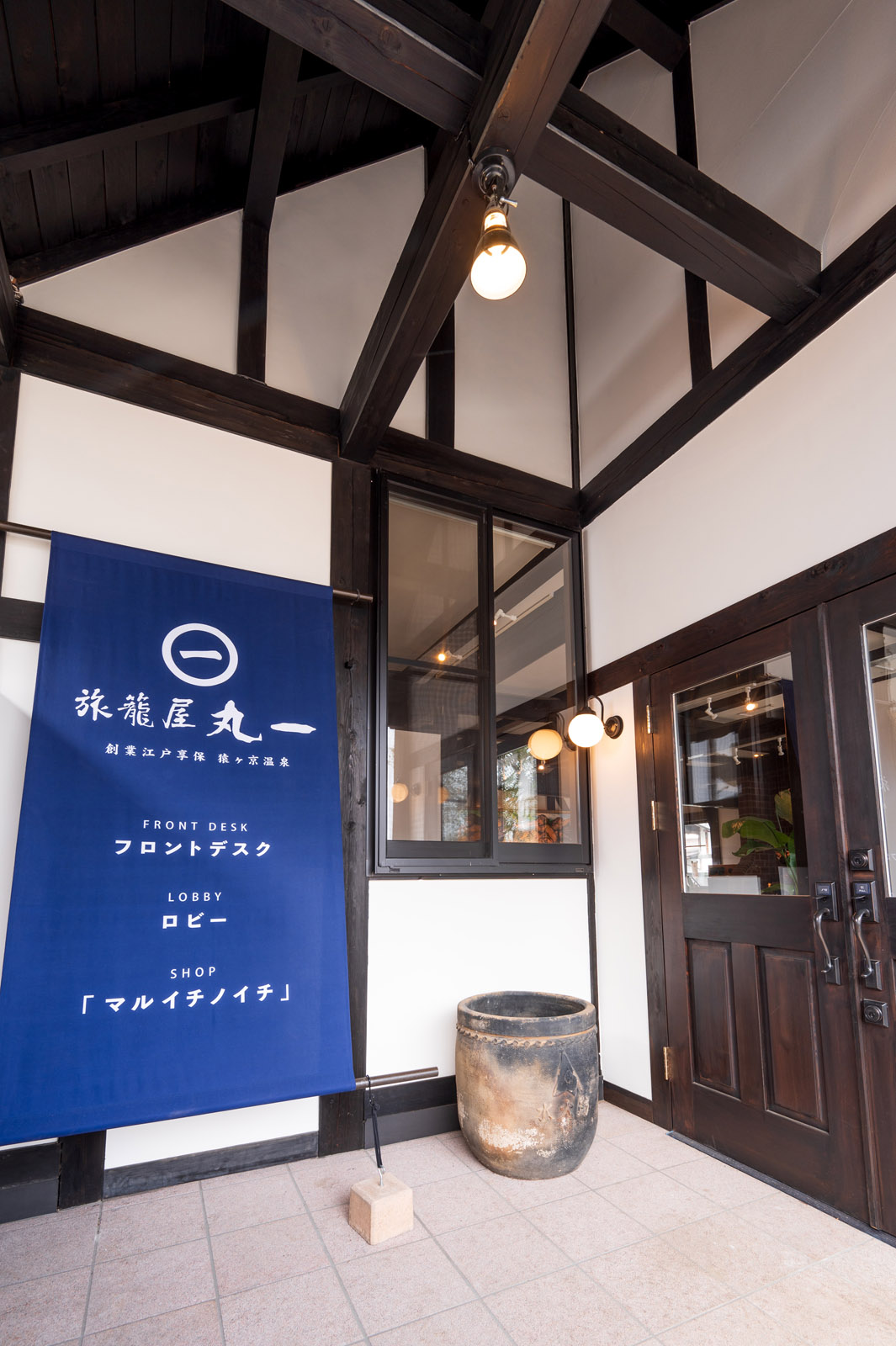 旅籠屋丸一の青い暖簾と木の扉があるフロント入口