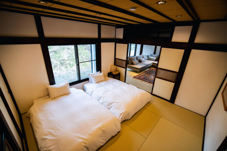 旅籠屋丸一の客室・寛畝にある二台のベッドと奥の居間