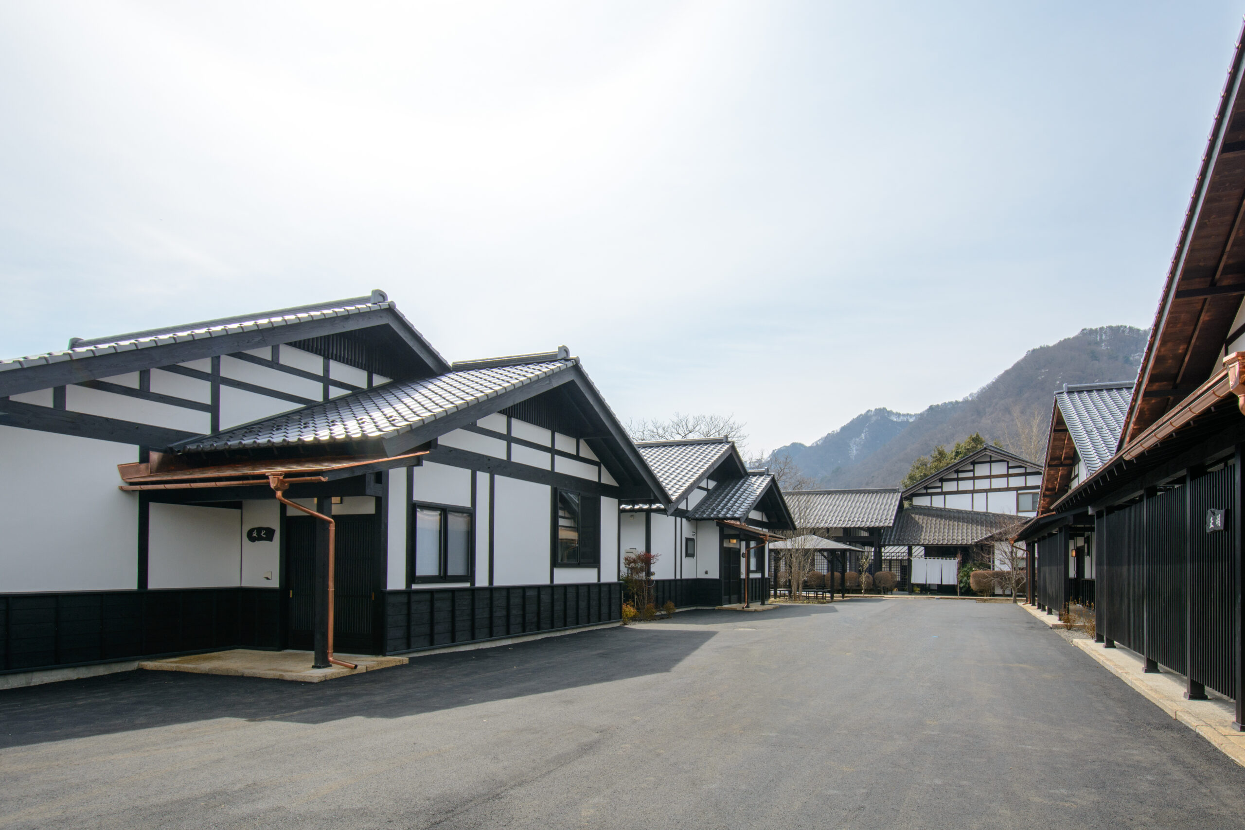 白壁と黒い柱の離れが中庭に並ぶ旅籠屋丸一の外観