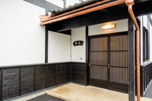 細い縦格子の玄関戸と白壁が見える旅籠屋丸一の離れ友七